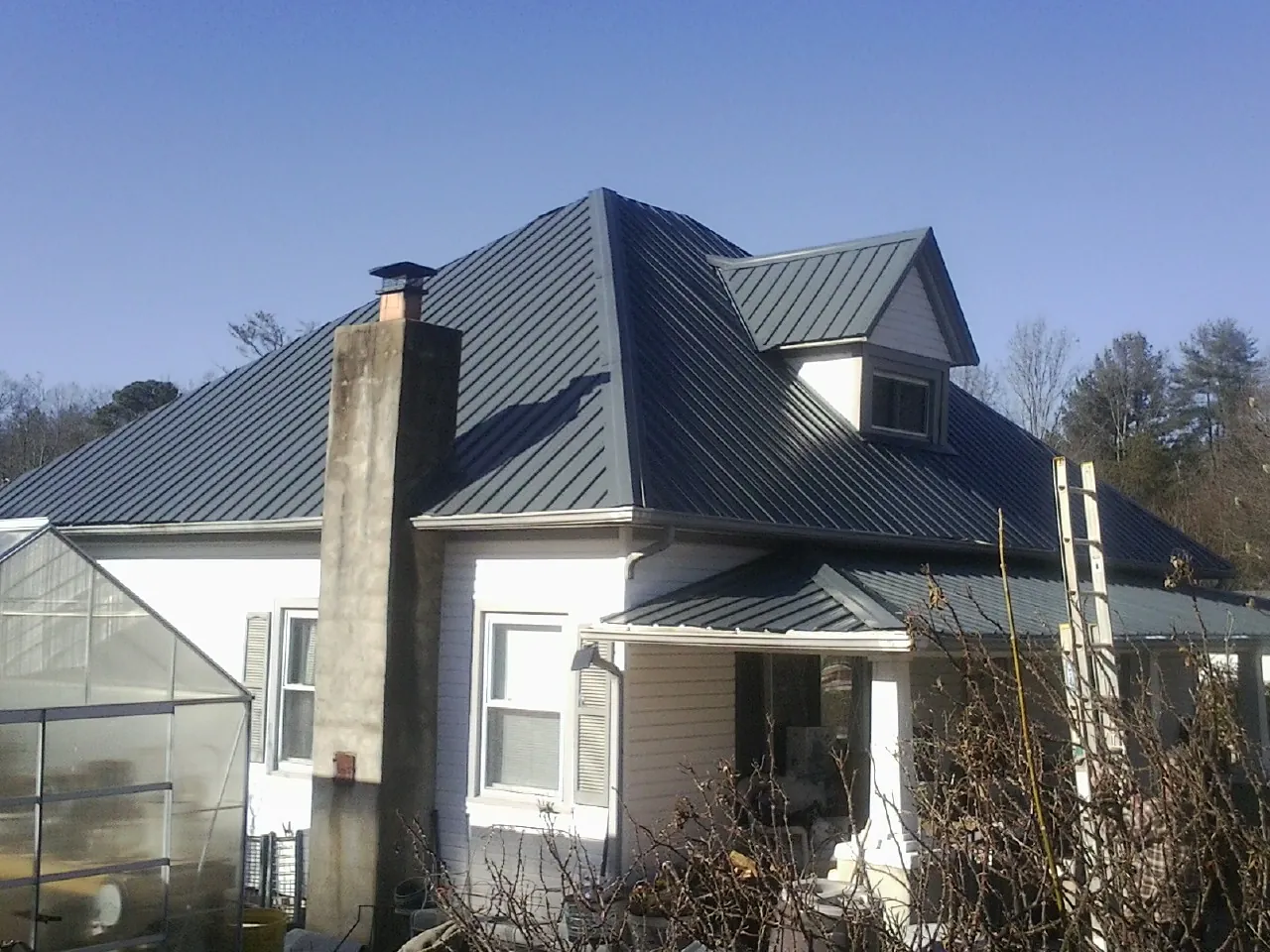 Dark blue standing seam metal roof on a white farmhouse with dormer — Slate & Tile Roof Repair by Roofing Brothers in Jordan Valley