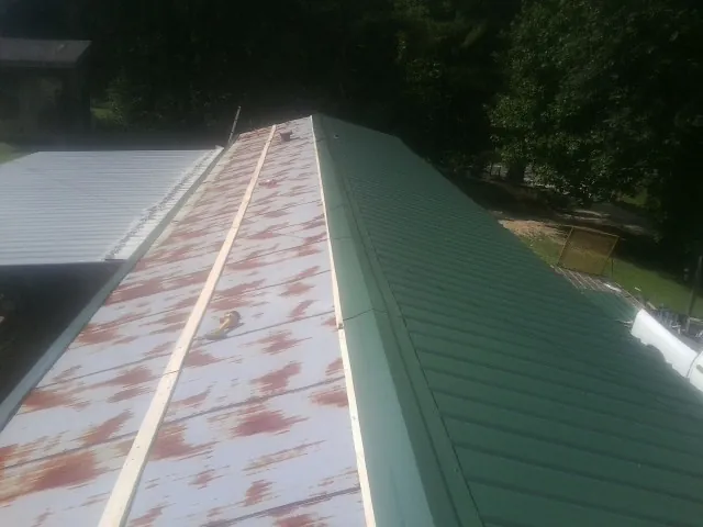 Old rusted panels beside newly installed green metal roofing — Wind Damage Roof Repair by Roofing Brothers in Jordan Valley