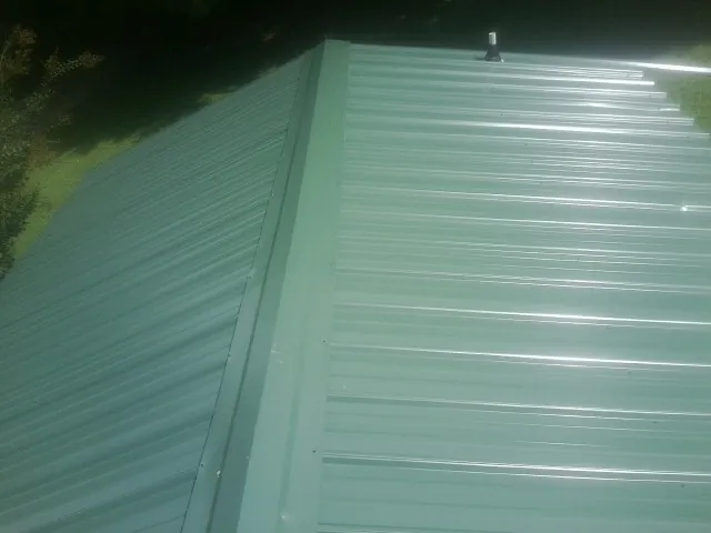 New green metal panels meeting at the ridge of a roof — Flat Roof Repair work by our crew in Jordan Valley