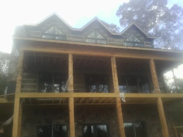 Dormers and porch framing on a large log home under construction — Roof Coating work by our crew in Jordan Valley