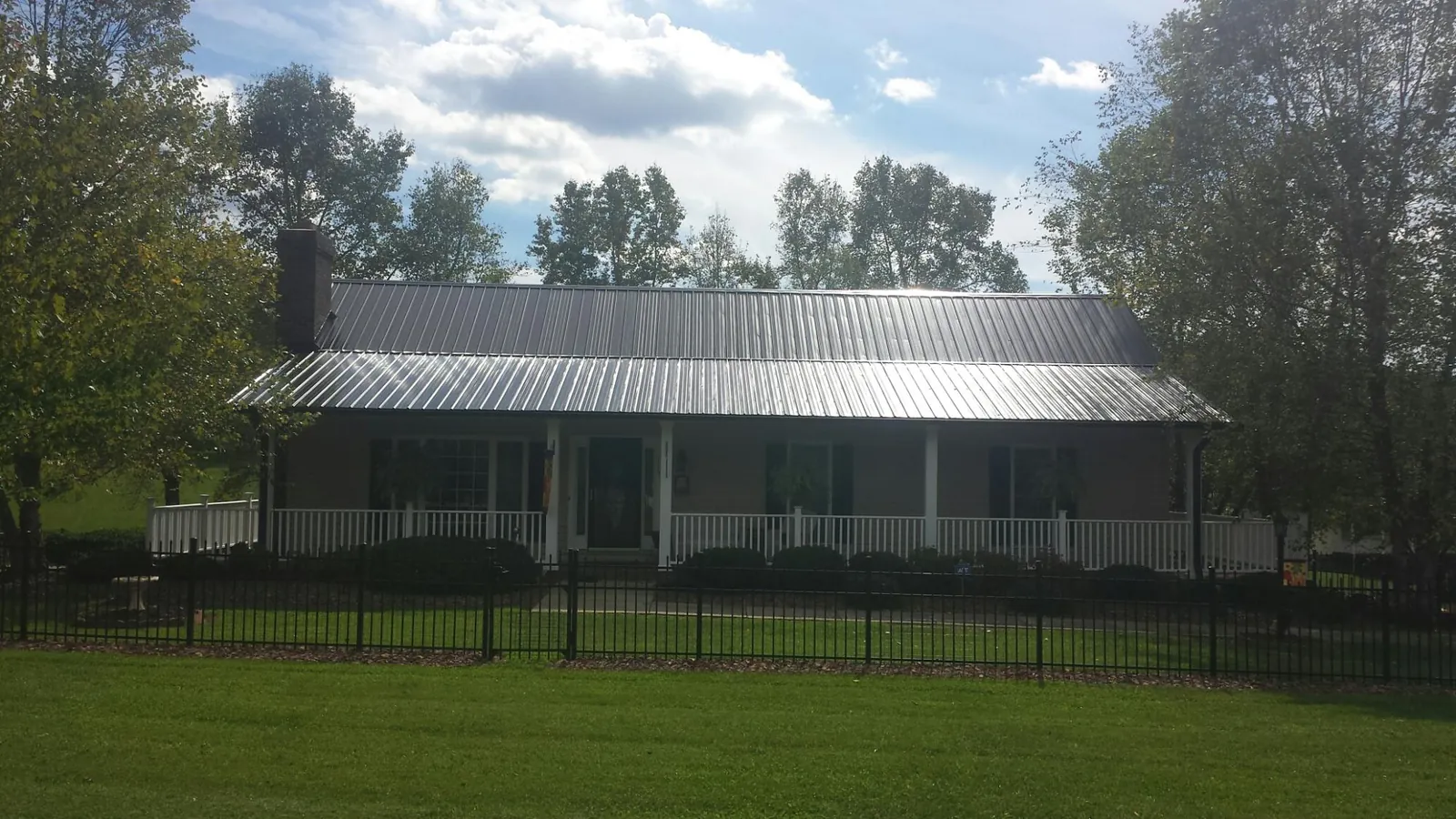 Gray metal roof on a brick ranch with a full width front porch — Gutter Guard Installation work by our crew in Jordan Valley