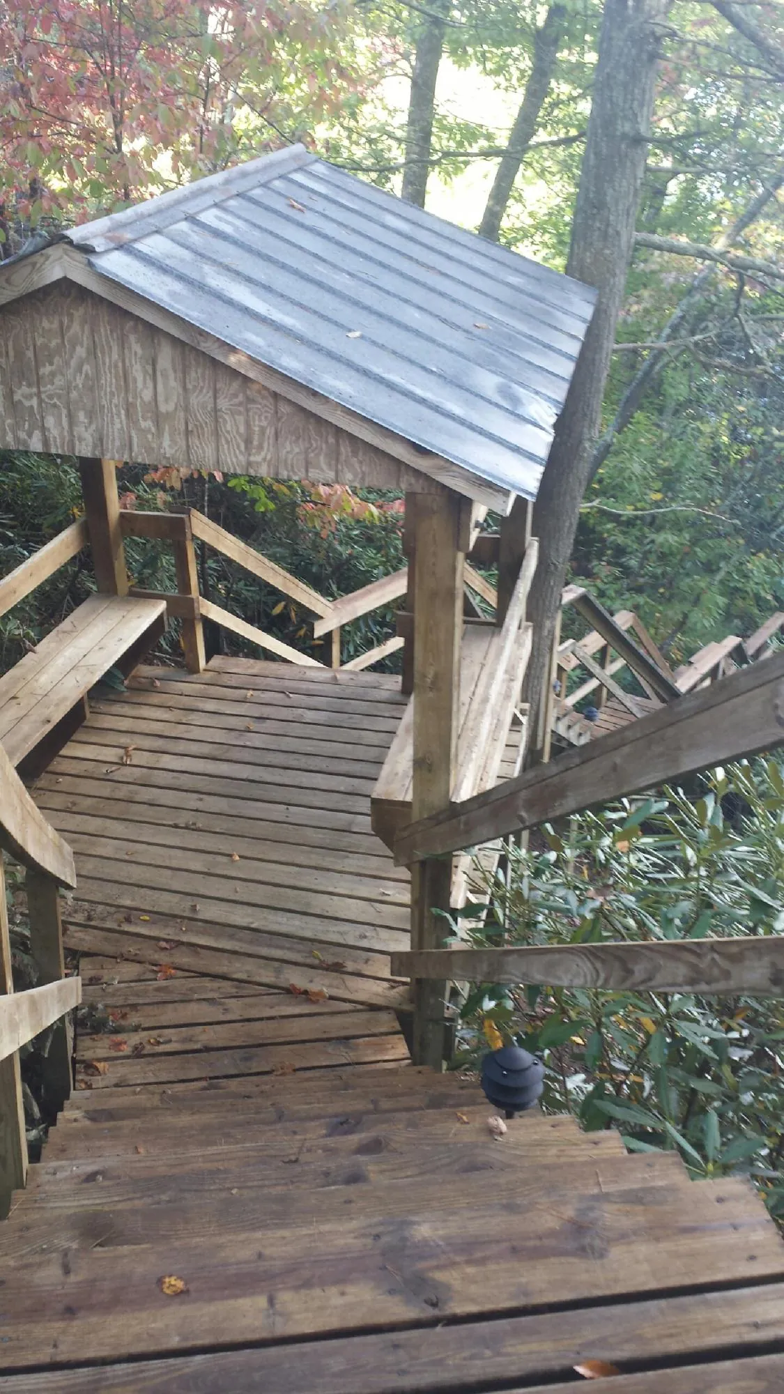Metal roofed shelter over wooden steps on a wooded walkway — Skylight Repair & Installation work by our crew in Jordan Valley