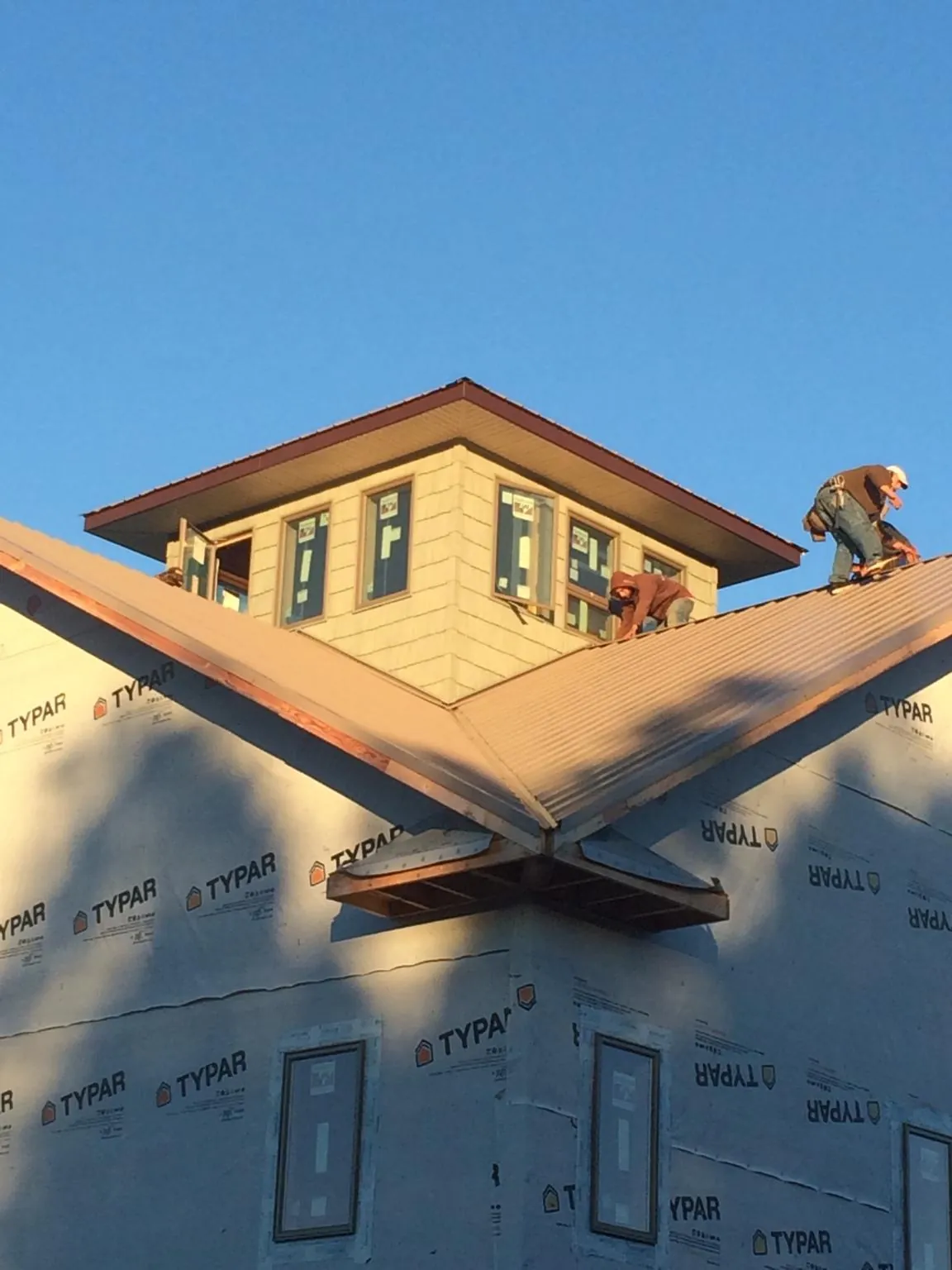 Roofers working around a rooftop cupola on a new metal roof at sunset — Roof Waterproofing in Jordan Valley by Roofing Brothers